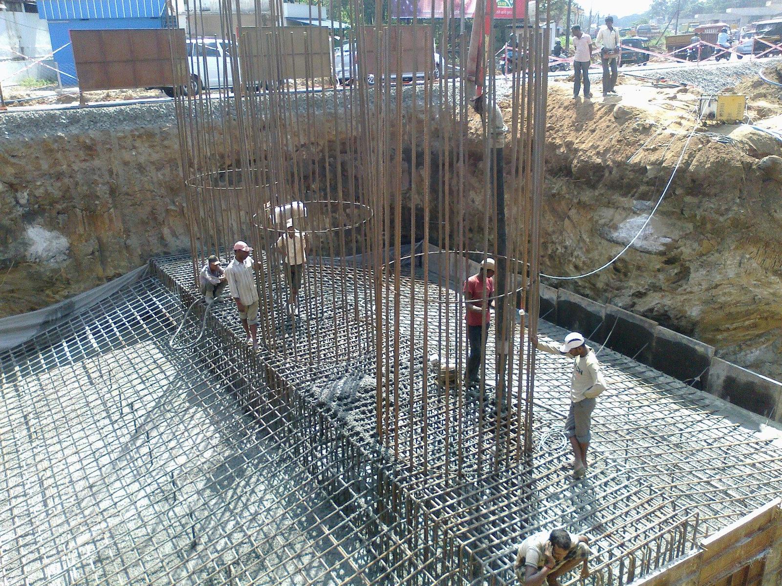 Workers placing concrete on a reinforced foundation in India